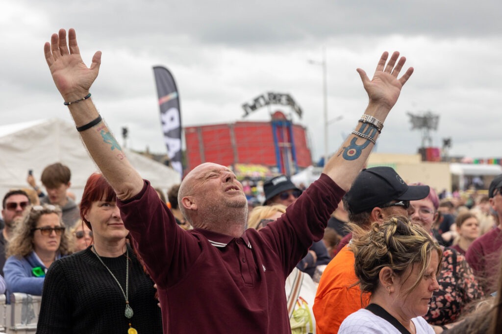 A man looks towards the sky with his arms outstretched during a concert