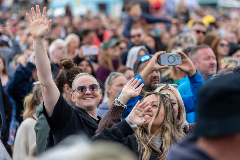Someone in the crowd spots the camera and waves