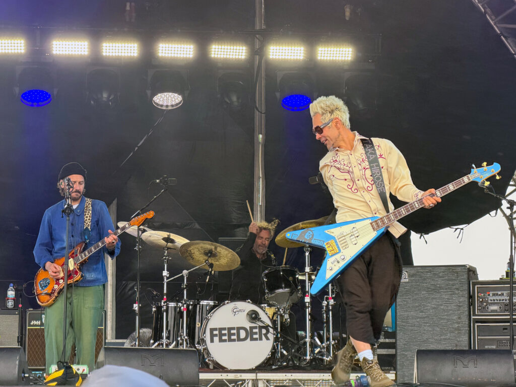 A guitarist with white hair and an extravagant blue guitar on stage