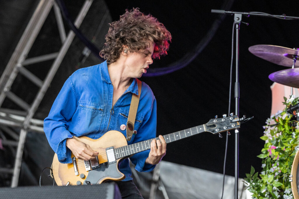 A male guitarist in a blue shirt performs on stage