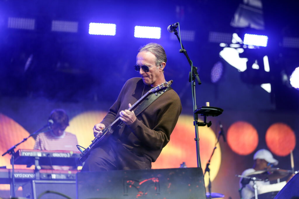 A guitarist on stage with his keyboard player in the background