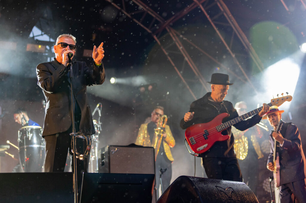 The lead singer of a band points at the crowd while he and the rest of his band perform