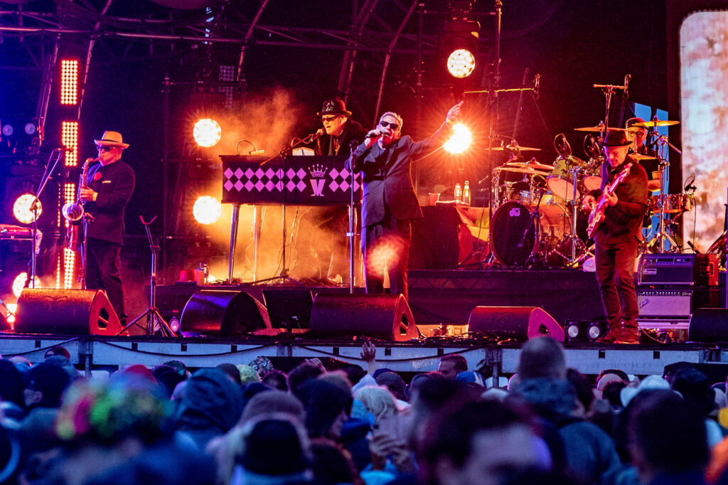 View of a band on stage taken over the heads of the large crowd