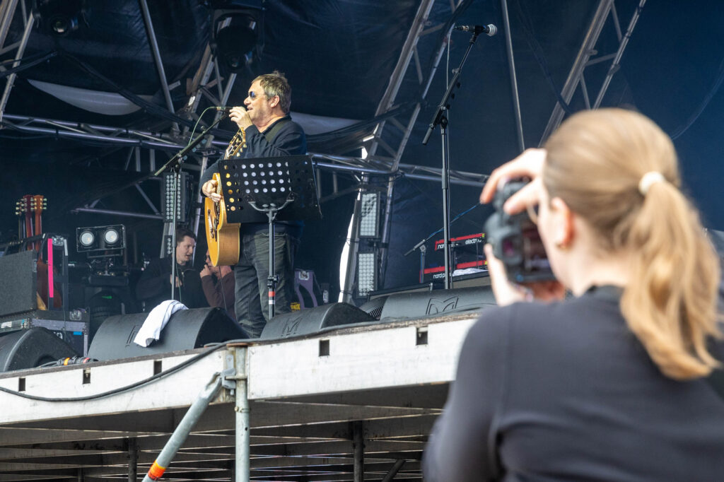 A photographer taking a picture of a guitarist on stage