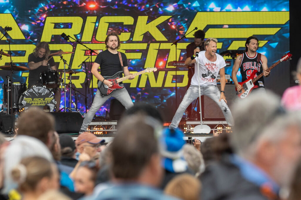 Five members of the Rick Parfitt band as seen through the heads of fans at a concert