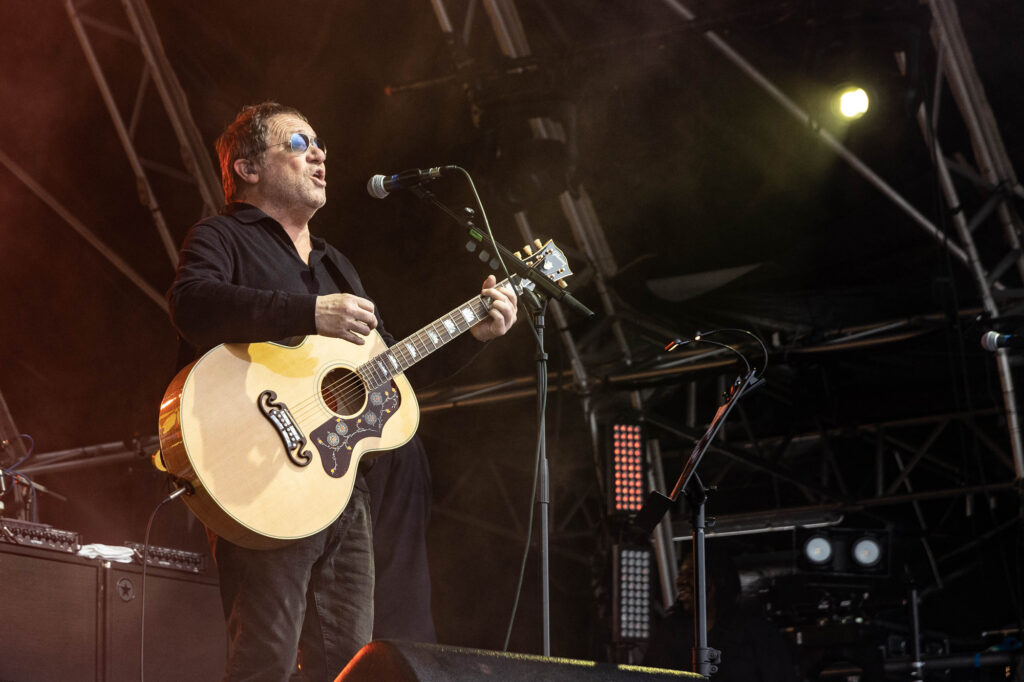 A man dressed in black with a guitar on stage
