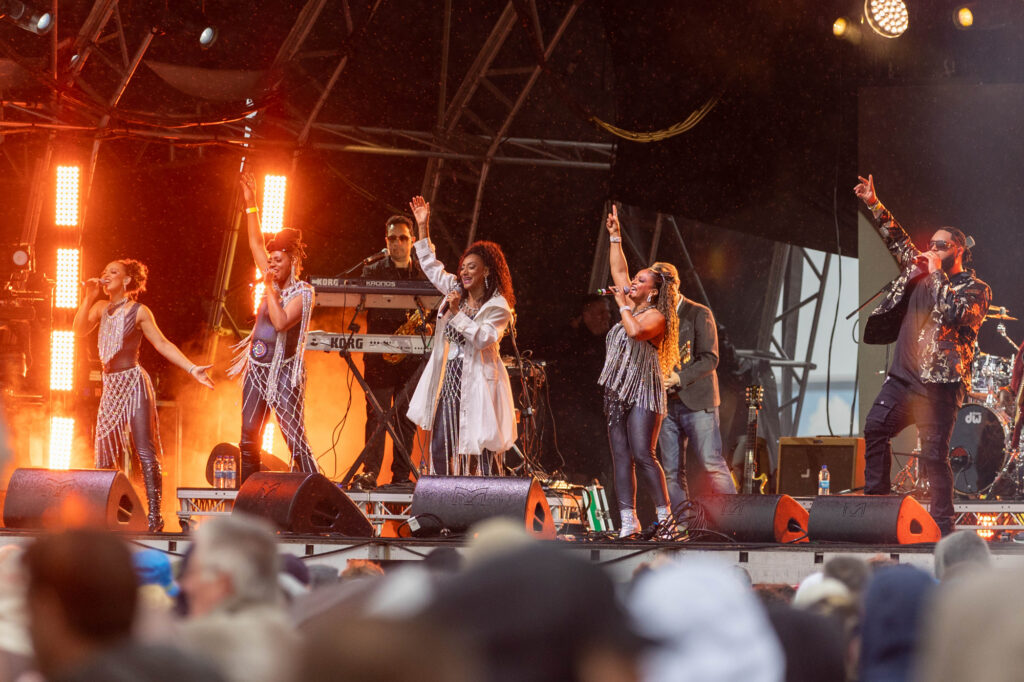 Five members of the Sister Sledge pop group raise their right hand while performing on stage