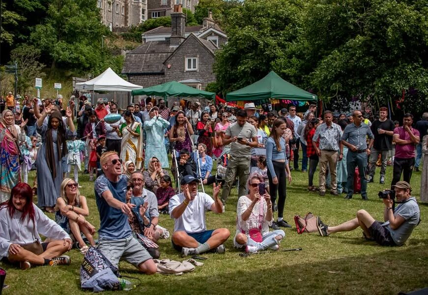 A group of people sit in Grove Park clapping their hands