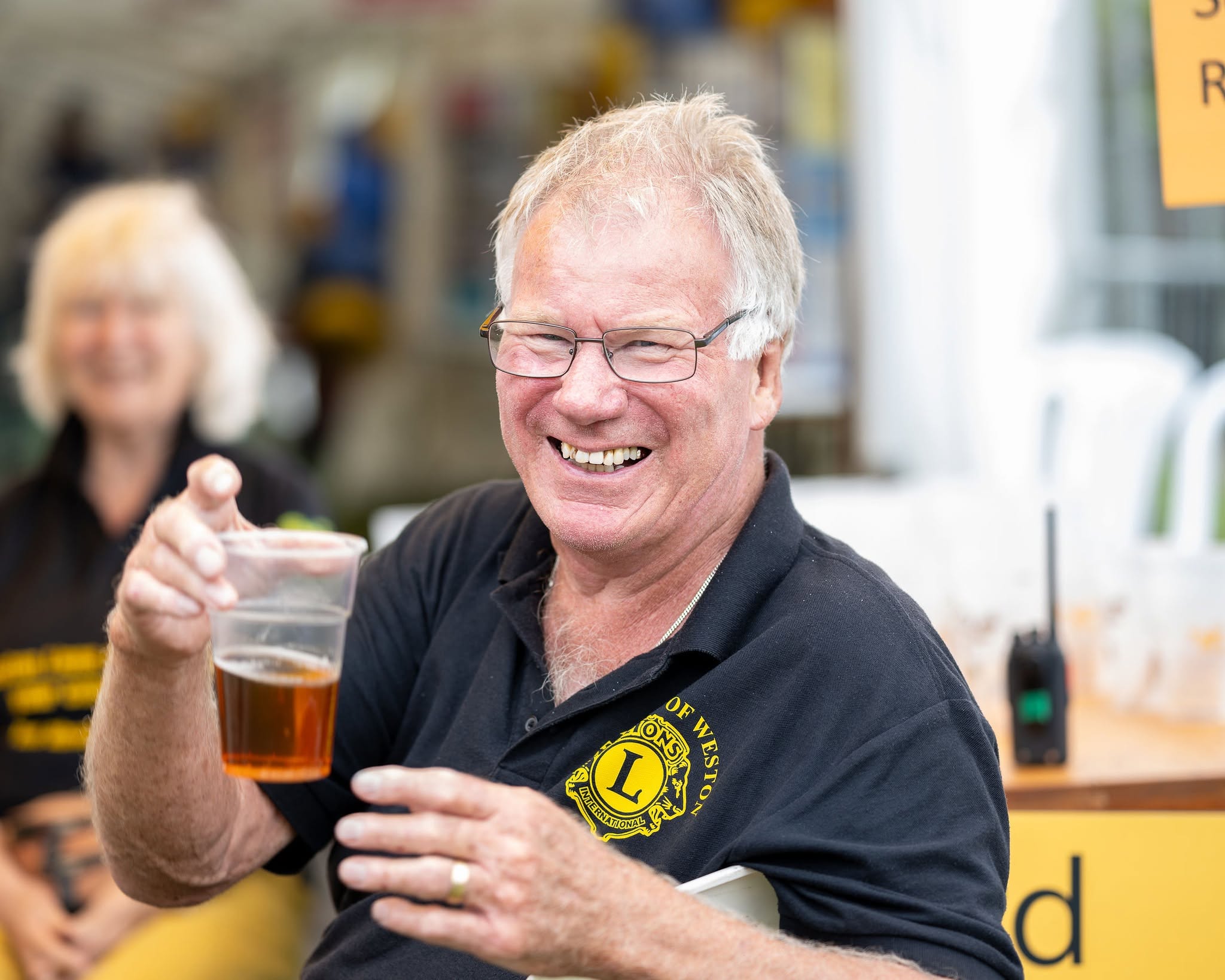 A man stands smiling holding a half pint of beer