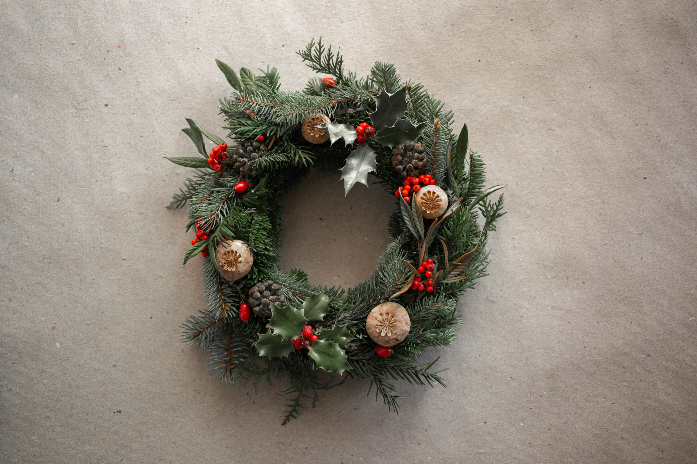 On a grey background, a wreath with gold, red and white ornaments