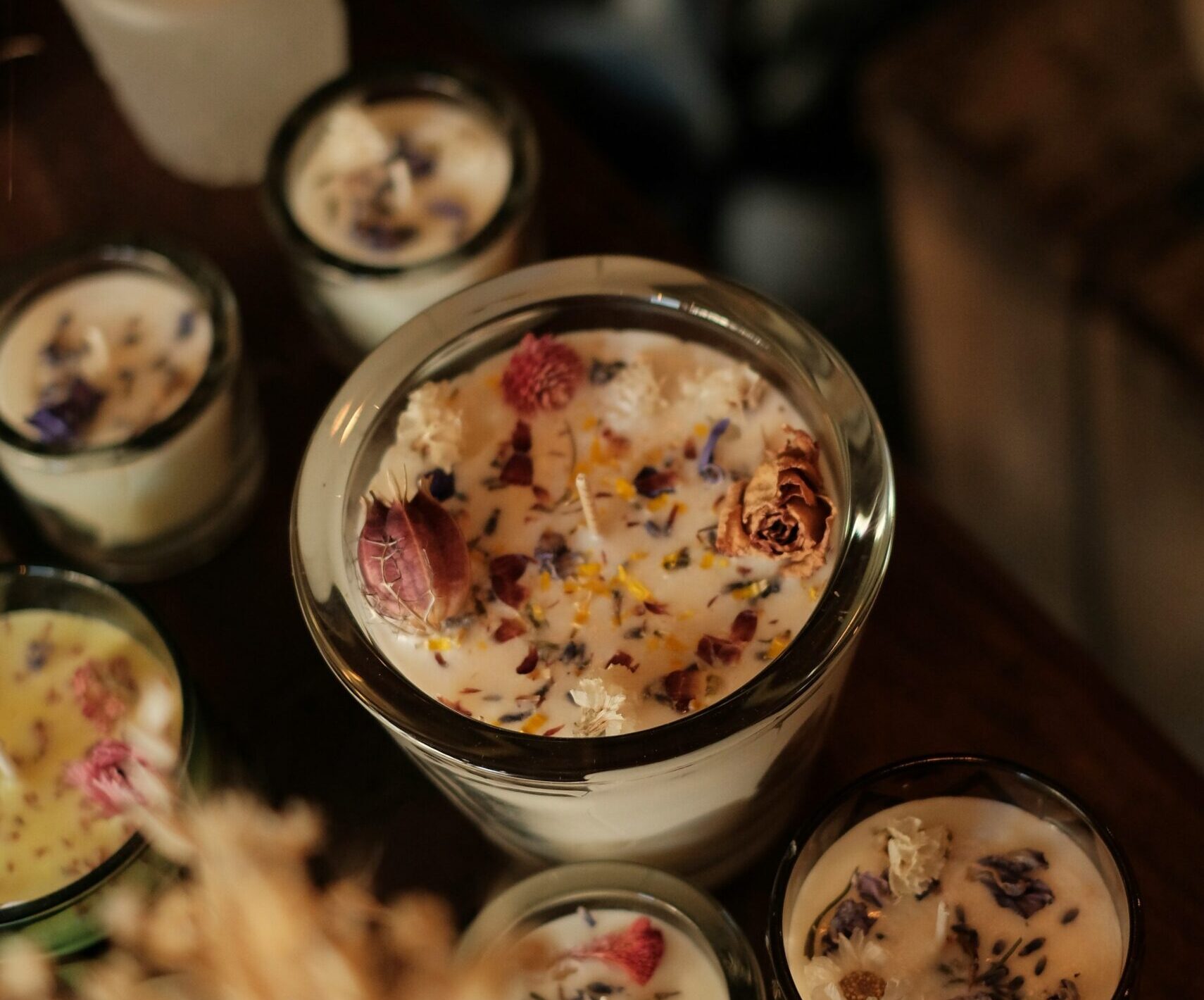 A row of candles in glass jars with flowers in the top of them