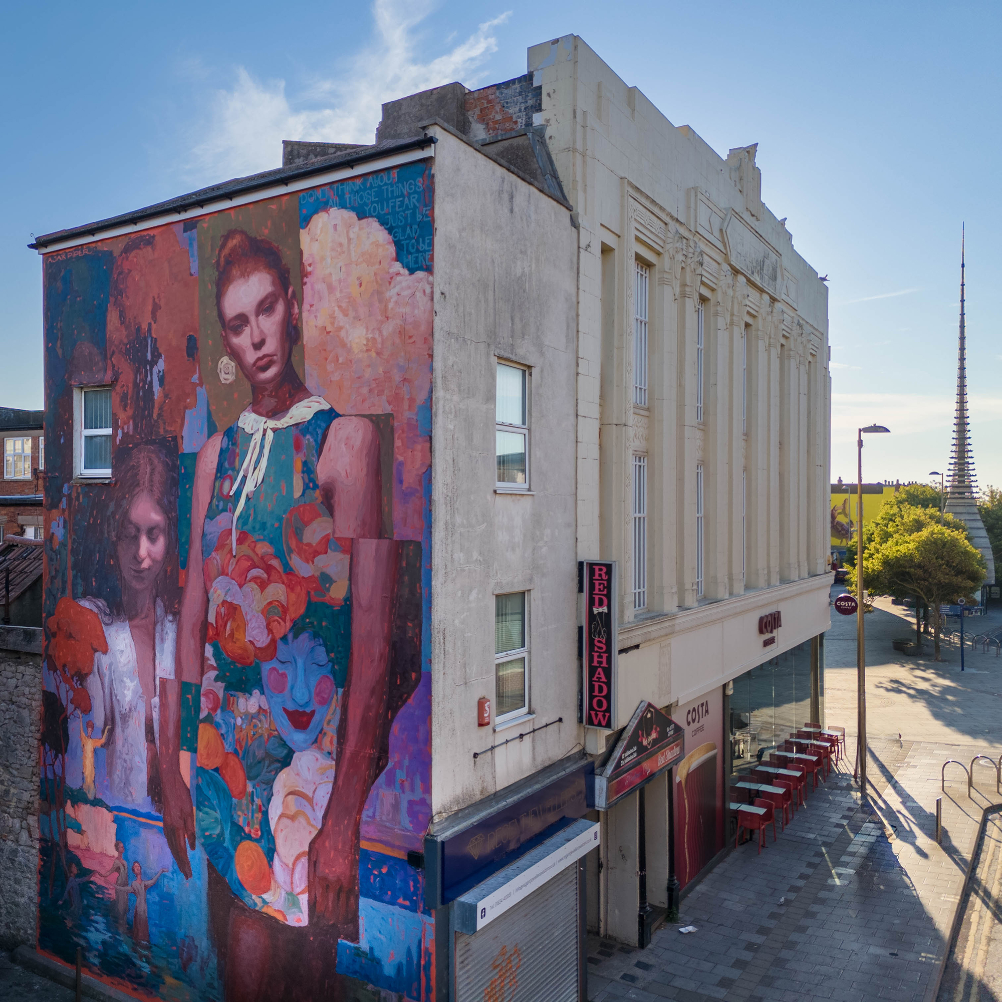 A giant street mural on the end of a tall building featuring two women