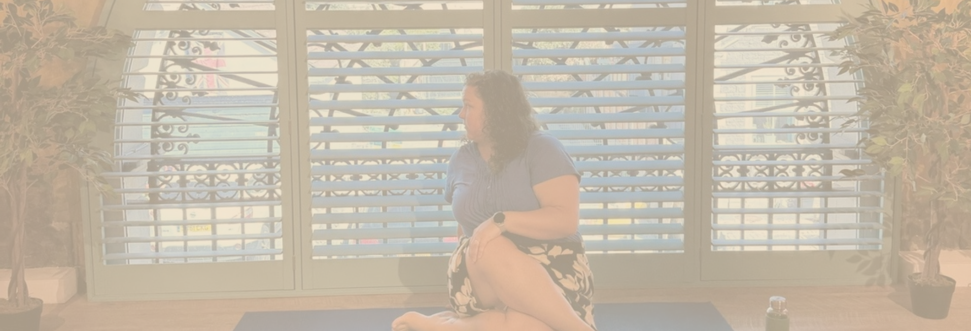 A woman sits looking to the side in front of a huge semi-circular window