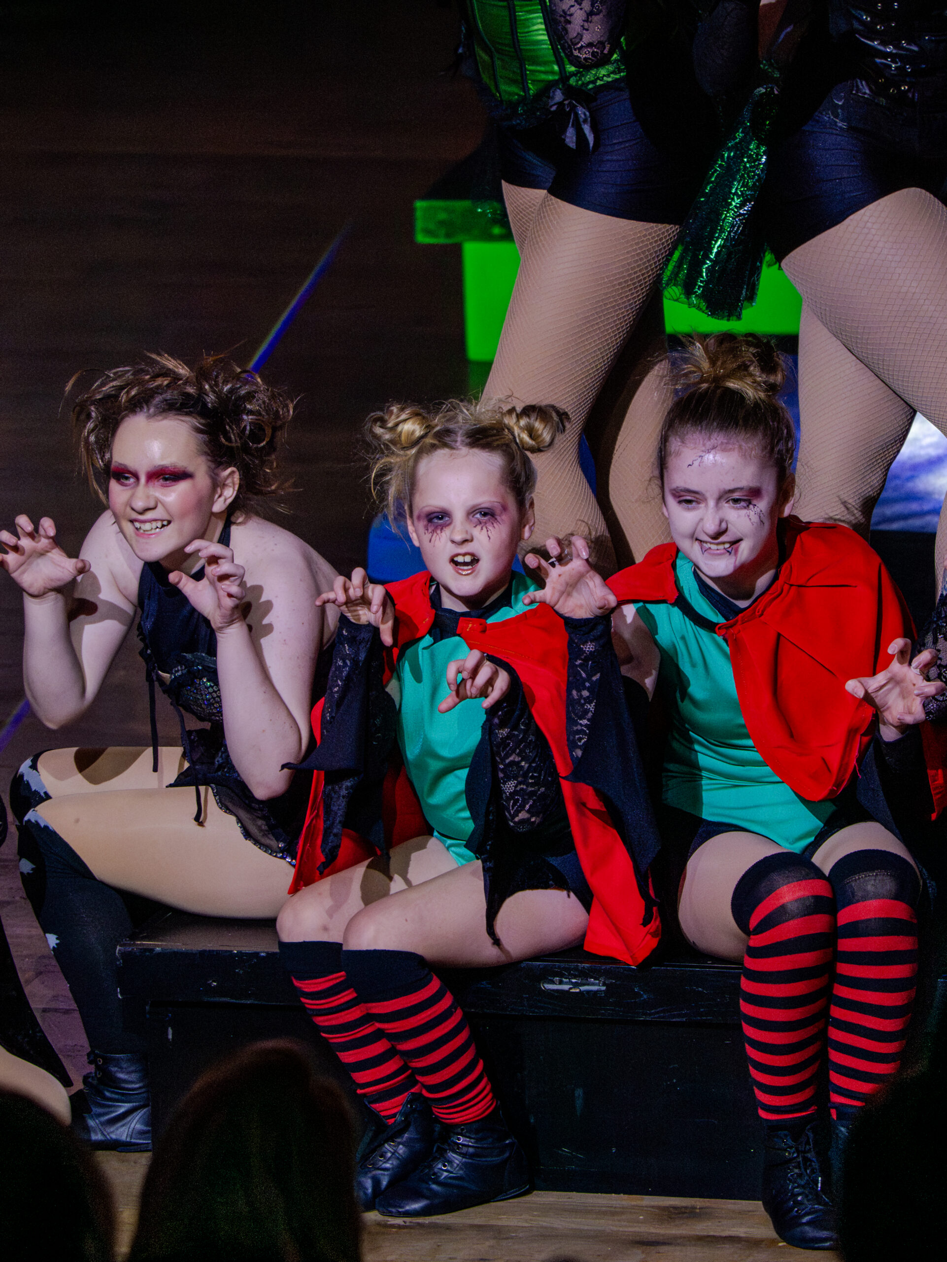 A group of girls dressed as witches sit in a line
