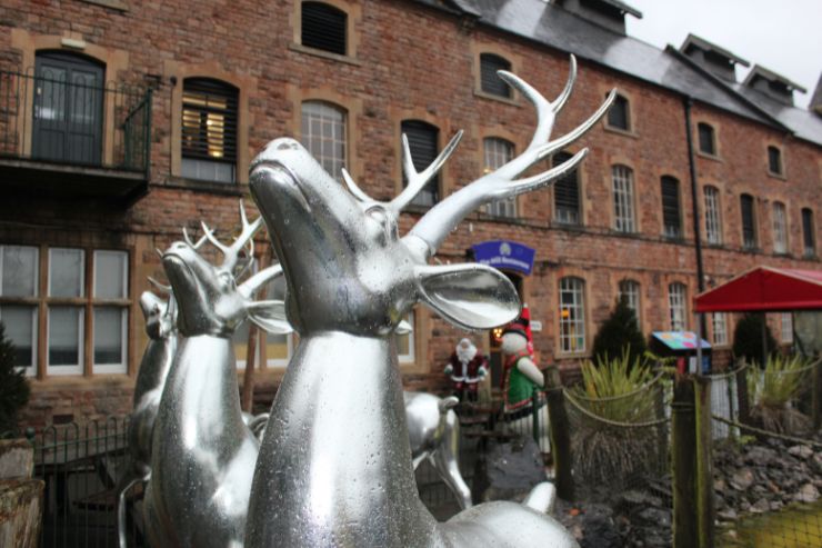Silver statues of reindeer. Behind a brick building